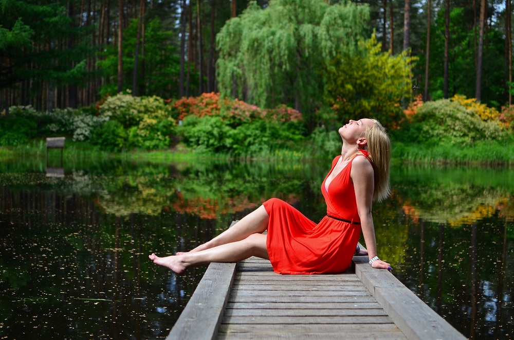  woman in red dress sitting on a pier above a lake, creating affirmations