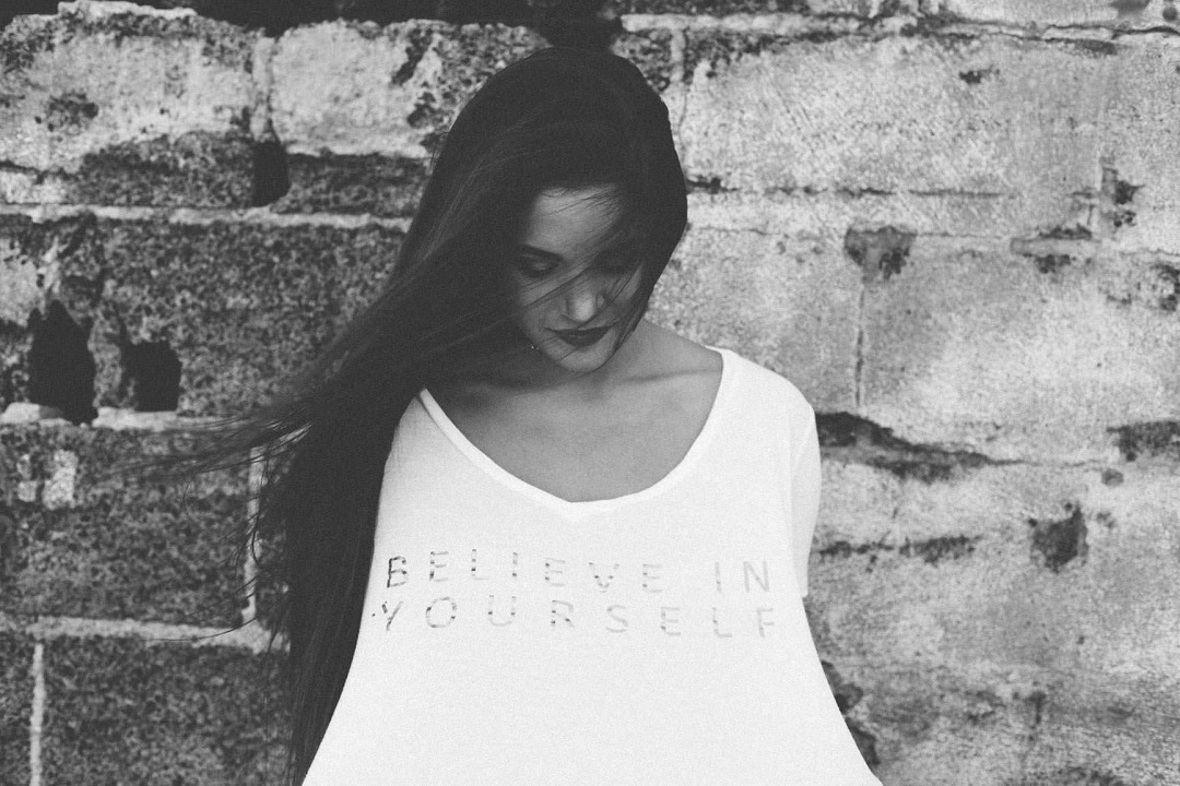 woman in white t-shirt with lettering Believe in Yourself, symbolizing the power of affirmations