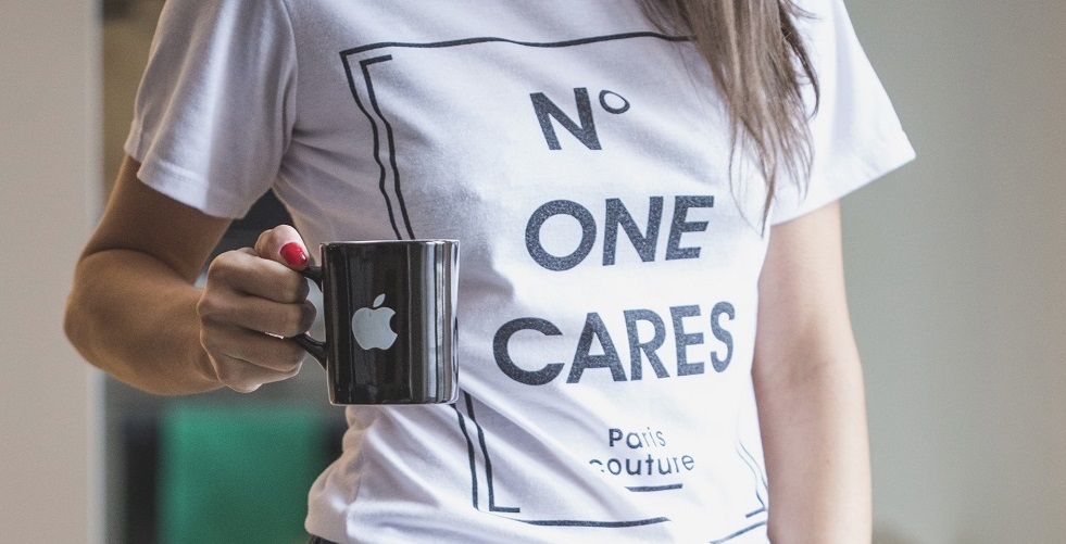 woman with apple coffee mug and wearing a t-shirt that says n o one cares, showing the power of self care first