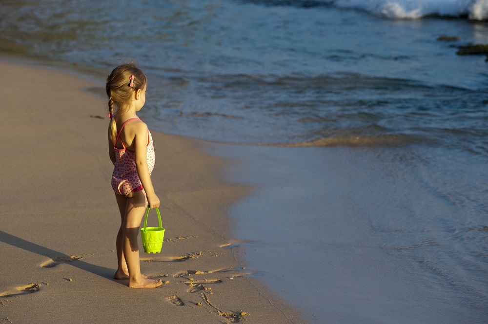 little girl is playing in the sand on the ocean, symbolizing the difficulties of setting boundaries