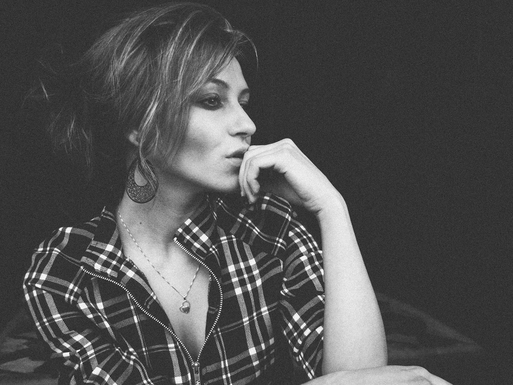 woman in a black and white picture with hand on her lips, hair up, earrings and black and white blouse, symbolizing the power to know your needs