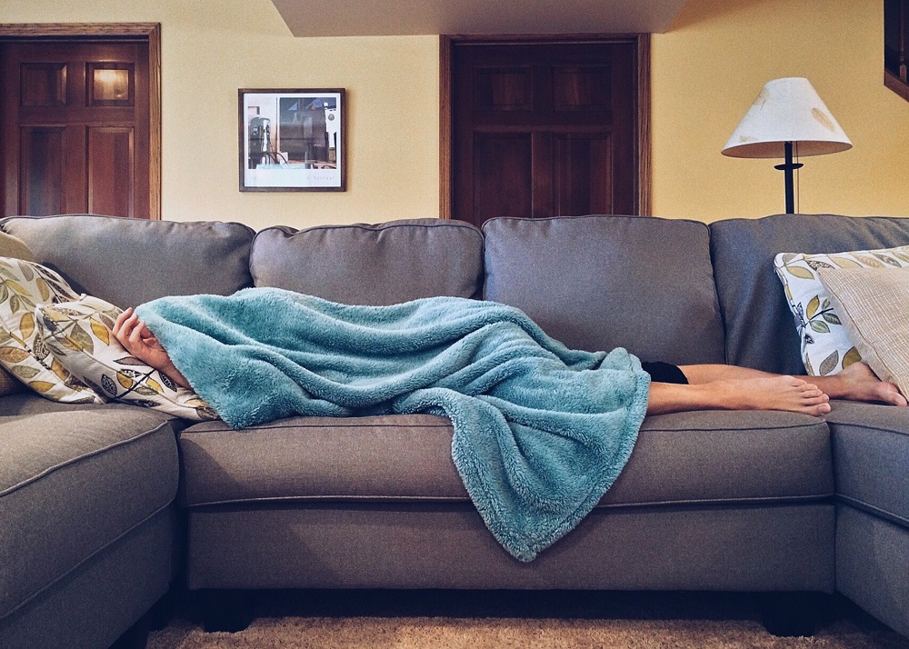 woman laying on the sofa, having a blanket hold over her head, stop judging yourself and start loving yourself first