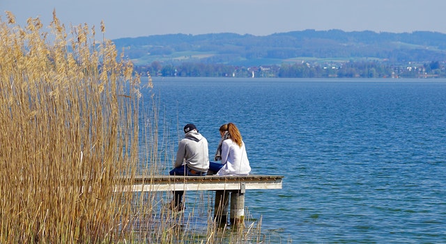 a couple sitting on a pier on a lake, keep peace with your spouse when you are upset