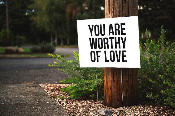 white sign with black letting on a tree, saying you are worthy of love, inner child healing