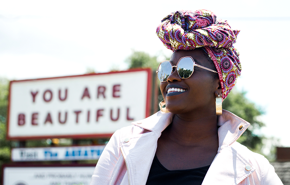 an African American woman in front of a sign You Are Beautiful, inner child healing