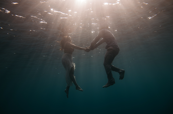 a couple dressed swimming in the ocean and holding hands underneath the water, good relationship rules