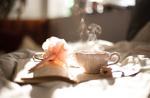 an open journal, a rose pen, and a cup with hot beverage, symbolizing how to be a better mom