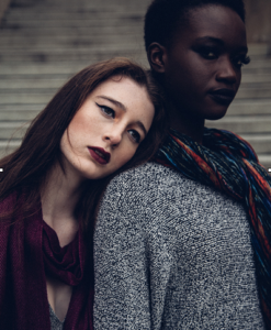 woman with dark hair and white skin color, leaning on a woman with black skin color and black hair, both in winter outfit, divine feminine energy