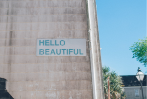 Concrete wall in a residential neighborhood, sign on wall says hello beautiful