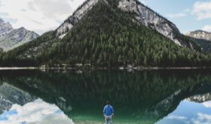 mountain reflection in the water, man is watching it, being vulnerable helps you to see your most beautiful authentic you