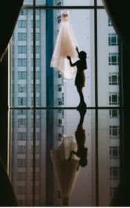 a woman in a highrise in front of a white wedding dress, hanging on a glass window, Criticism in Relationships: How to Change Your Words from Blame to Encouragement